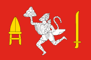 red, white image of Hanuman between two gold weapons
